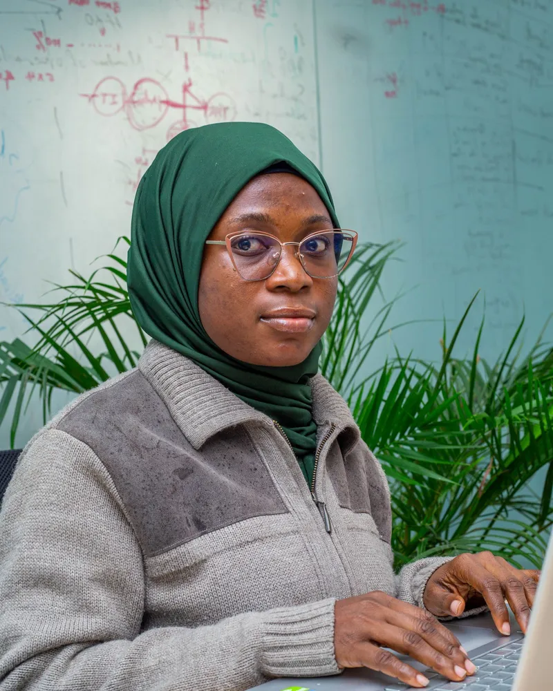 A woman in a green headscarf working at a laptop in Lagos, Nigeria.